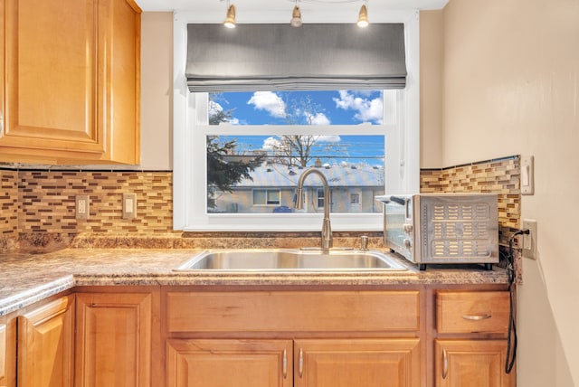 kitchen with light countertops, tasteful backsplash, light brown cabinetry, and a sink