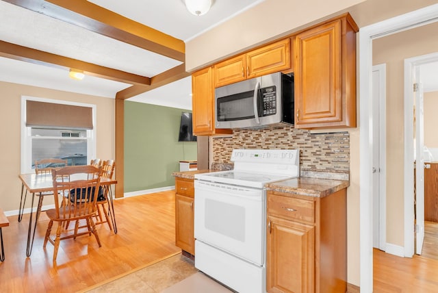 kitchen with stainless steel microwave, backsplash, light countertops, light wood-style floors, and white electric range oven