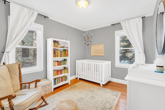 bedroom featuring radiator, light wood-style floors, and baseboards