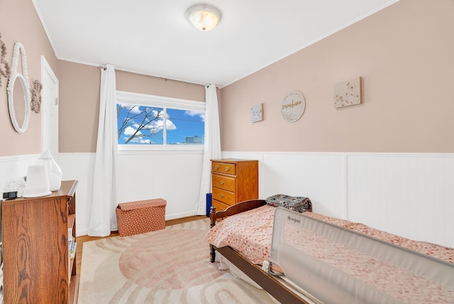 bedroom featuring wood finished floors and wainscoting