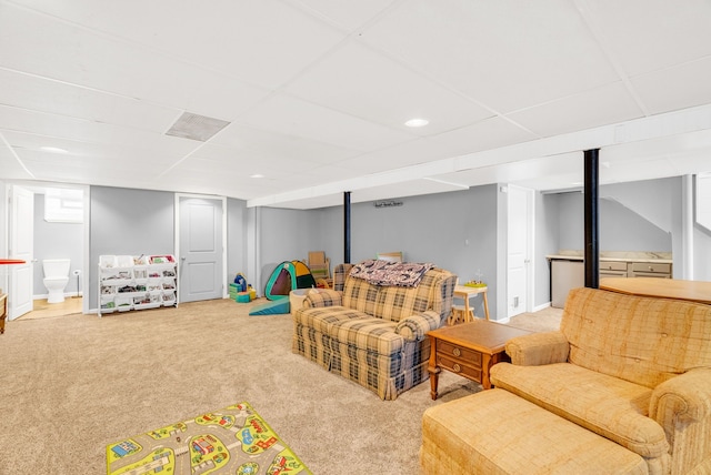 carpeted living area with a paneled ceiling