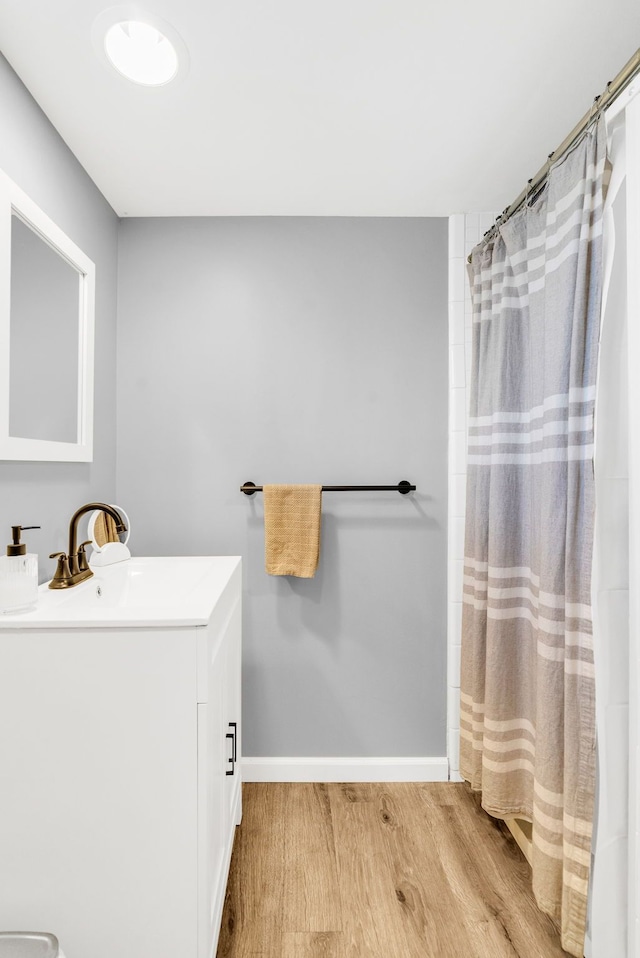 full bathroom with vanity, a shower with shower curtain, wood finished floors, and baseboards