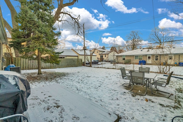 snowy yard featuring outdoor dining space, fence private yard, and a residential view