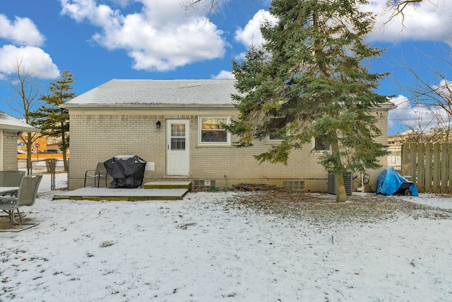 snow covered property with entry steps, a gate, fence, and brick siding