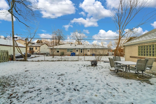 snowy yard featuring outdoor dining area and fence