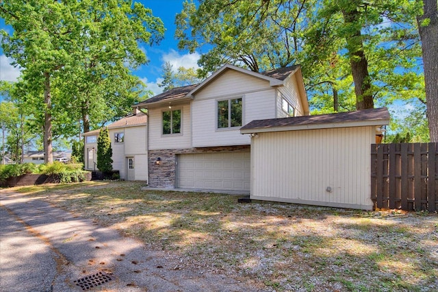 view of side of home featuring an attached garage and fence