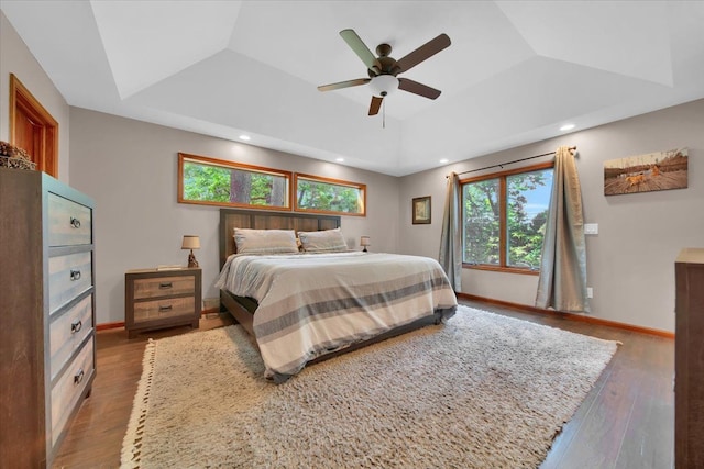 bedroom featuring recessed lighting, a raised ceiling, baseboards, and wood-type flooring