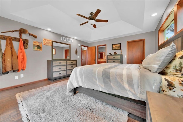 bedroom with wood finished floors, baseboards, visible vents, recessed lighting, and a raised ceiling