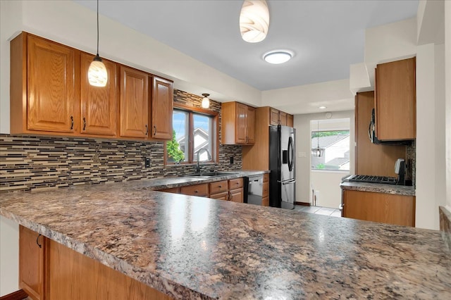 kitchen featuring tasteful backsplash, dishwashing machine, brown cabinets, stainless steel refrigerator with ice dispenser, and a sink