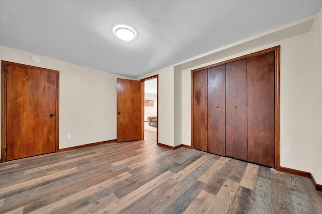 unfurnished bedroom with a closet, baseboards, and wood finished floors