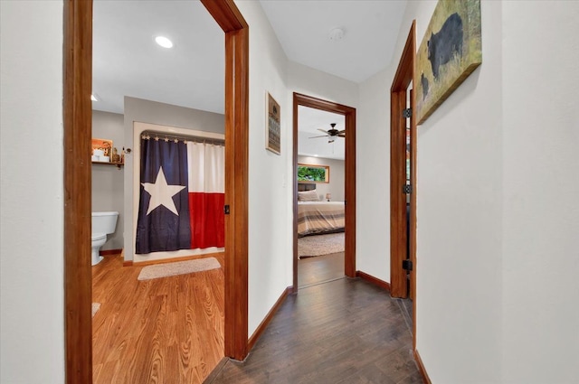 corridor featuring wood finished floors and baseboards