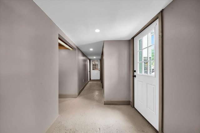 hallway with recessed lighting, baseboards, and concrete floors