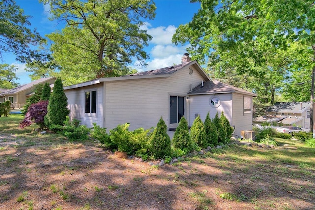 view of side of property with central air condition unit and a chimney