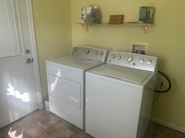 clothes washing area with stone finish flooring, independent washer and dryer, and laundry area