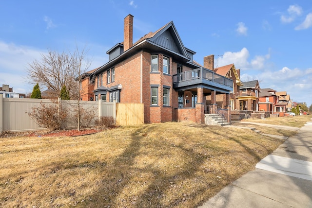 view of side of home featuring brick siding, a chimney, and fence