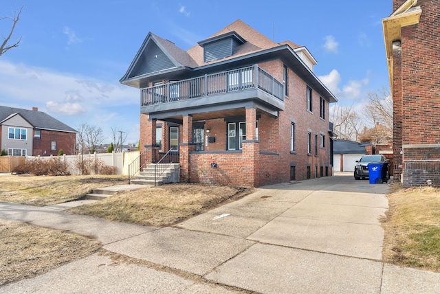 american foursquare style home featuring an outbuilding, brick siding, a balcony, and fence