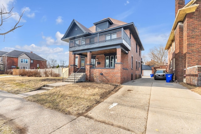 traditional style home featuring an outbuilding, a balcony, brick siding, and driveway