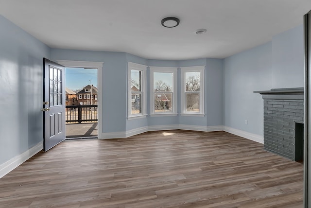 unfurnished living room featuring visible vents, plenty of natural light, baseboards, and wood finished floors