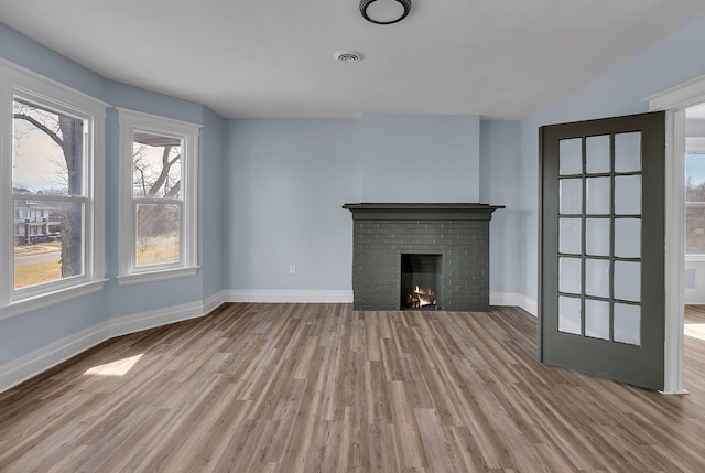 unfurnished living room with visible vents, light wood-style flooring, a fireplace, and baseboards