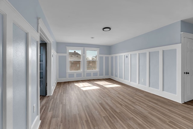 spare room featuring a decorative wall and wood finished floors