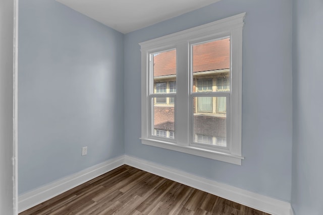 unfurnished room with baseboards and dark wood-type flooring