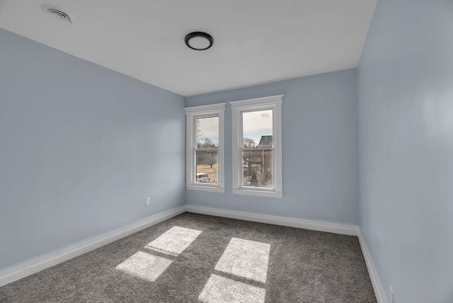 carpeted spare room featuring visible vents and baseboards