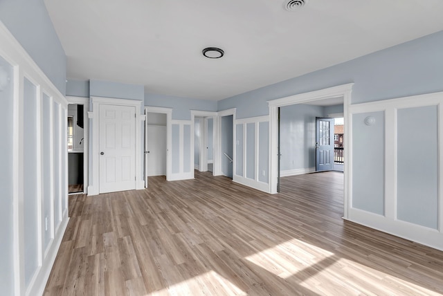 unfurnished bedroom featuring visible vents, baseboards, light wood-style floors, and multiple closets