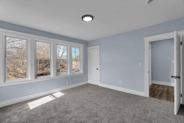 empty room featuring carpet flooring, visible vents, and baseboards