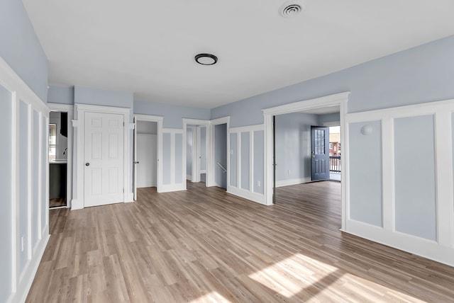 unfurnished bedroom with light wood-style flooring, baseboards, visible vents, and multiple closets