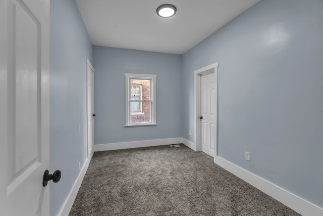 carpeted empty room featuring baseboards