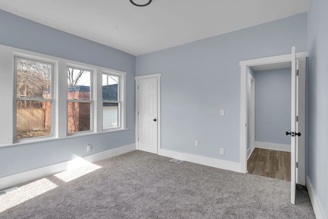 carpeted empty room with baseboards and visible vents