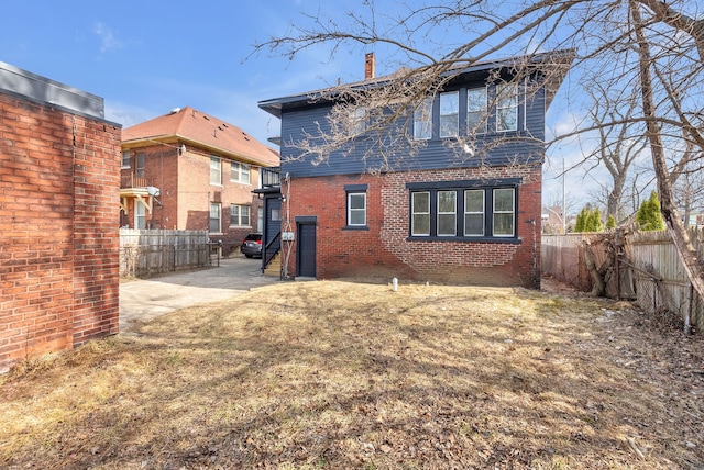 rear view of property with a fenced backyard, brick siding, a chimney, a patio area, and a lawn