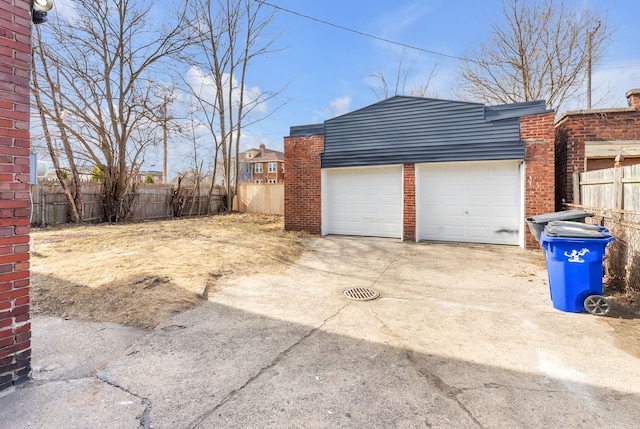 garage with concrete driveway and fence