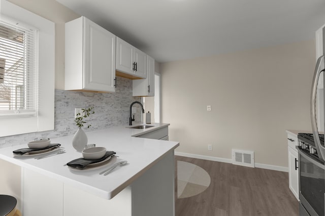 kitchen with visible vents, a kitchen bar, decorative backsplash, dark wood-style floors, and a sink