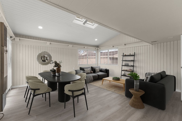 dining area featuring lofted ceiling with skylight and light wood-style floors