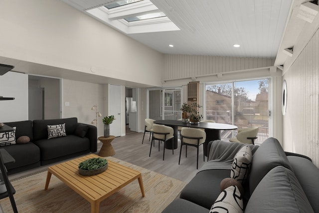 living area with lofted ceiling with skylight, recessed lighting, and light wood-style flooring