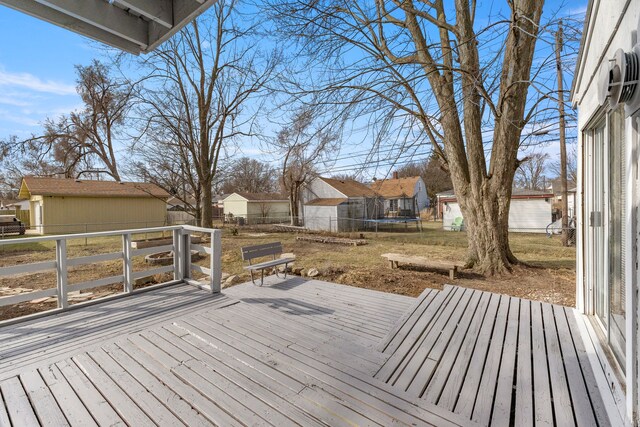 wooden terrace featuring a residential view, an outbuilding, a trampoline, and a fenced backyard