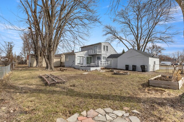 back of house with a garden, fence, and a lawn