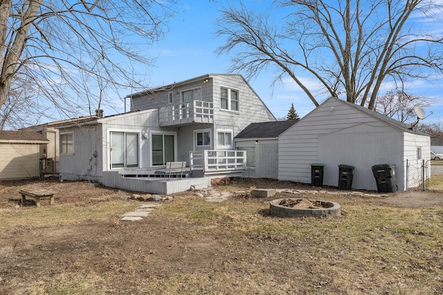 rear view of house with a balcony, a fire pit, and a wooden deck