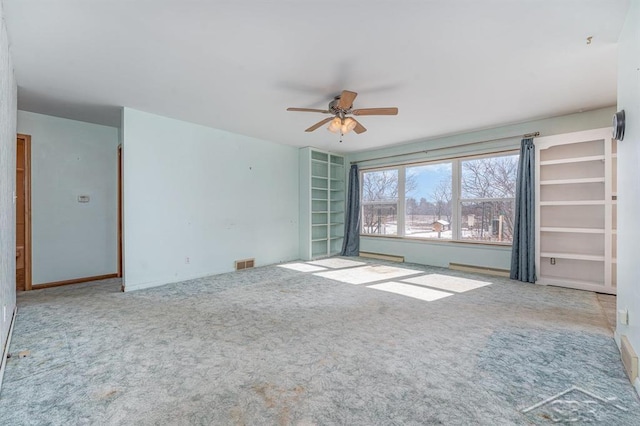 carpeted spare room with visible vents and a ceiling fan