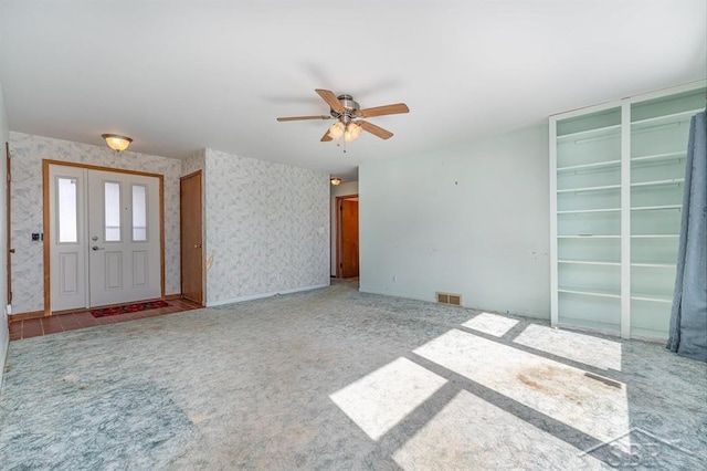 interior space with wallpapered walls, carpet, visible vents, and a ceiling fan