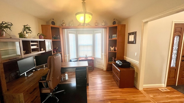 home office featuring light wood finished floors and vaulted ceiling