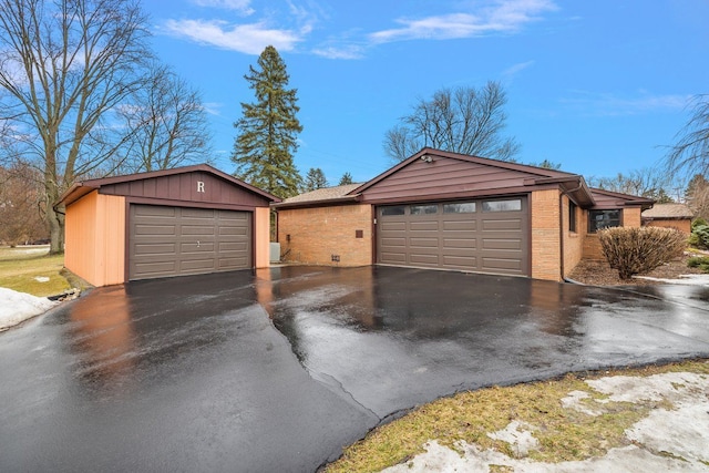 view of front of property featuring an outdoor structure, brick siding, and a garage