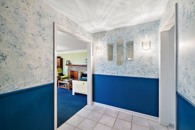 hall with tile patterned flooring, wainscoting, wallpapered walls, and carpet floors