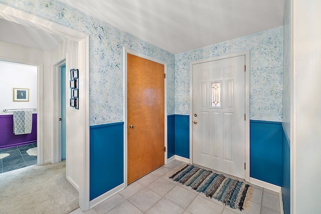 tiled foyer entrance with a wainscoted wall and wallpapered walls