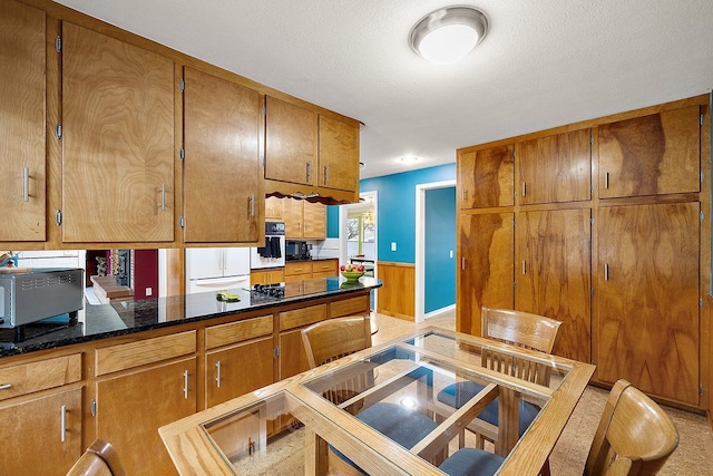 kitchen featuring a wainscoted wall, brown cabinets, and oven