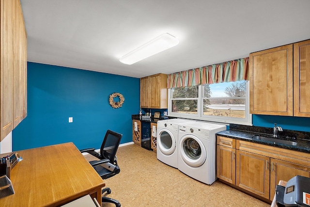 washroom featuring light floors, baseboards, cabinet space, a sink, and washer and clothes dryer