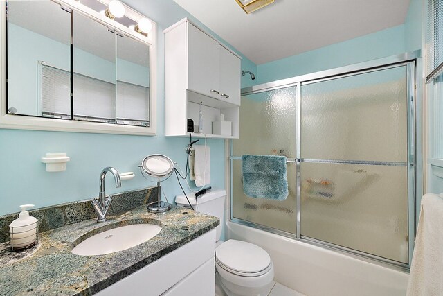 full bathroom featuring enclosed tub / shower combo, toilet, and vanity