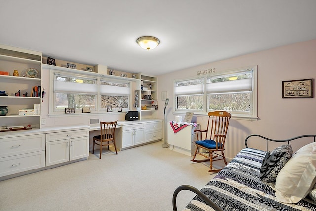 bedroom featuring light colored carpet and built in study area