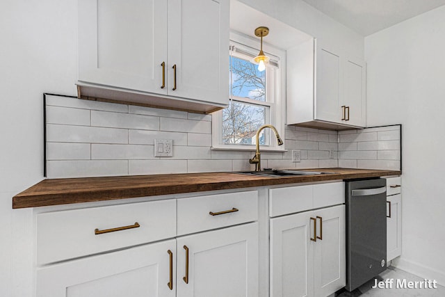 kitchen with a sink, tasteful backsplash, white cabinets, and butcher block counters